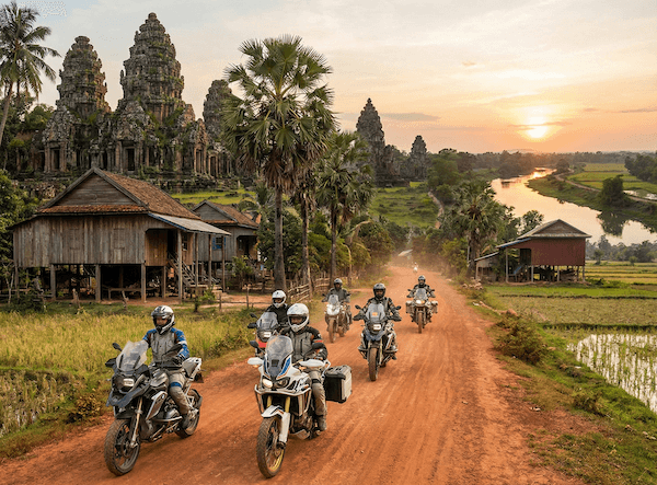 A group of riders on a dirt road past the temples of Cambodia at sunset