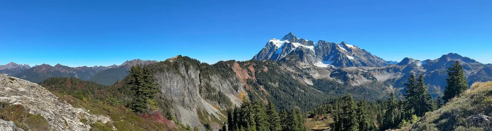 Panorama from Artist Point across forested ridges and rock to the snow-streaked summit of Mount Shuksan