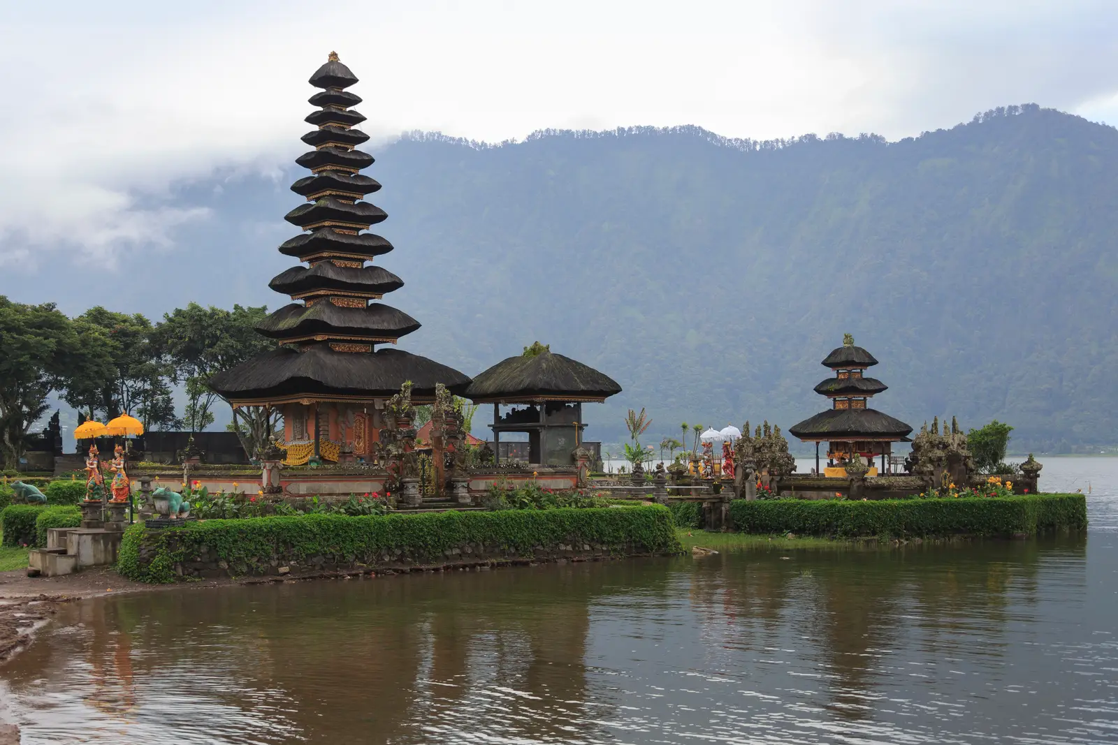 The eleven-tiered thatched shrine of Pura Ulun Danu Beratan and a smaller shrine on the shore of Lake Beratan, with misty forested hills behind