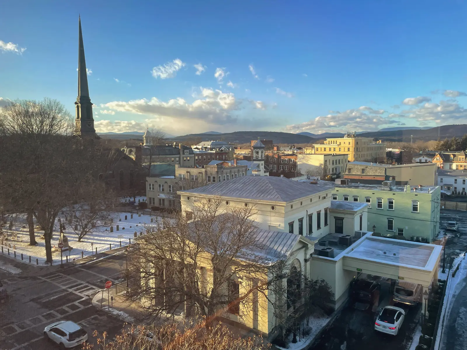 The spire of the Old Dutch Church above the snowy churchyard and the rooftops of Uptown Kingston, with the Catskills on the horizon