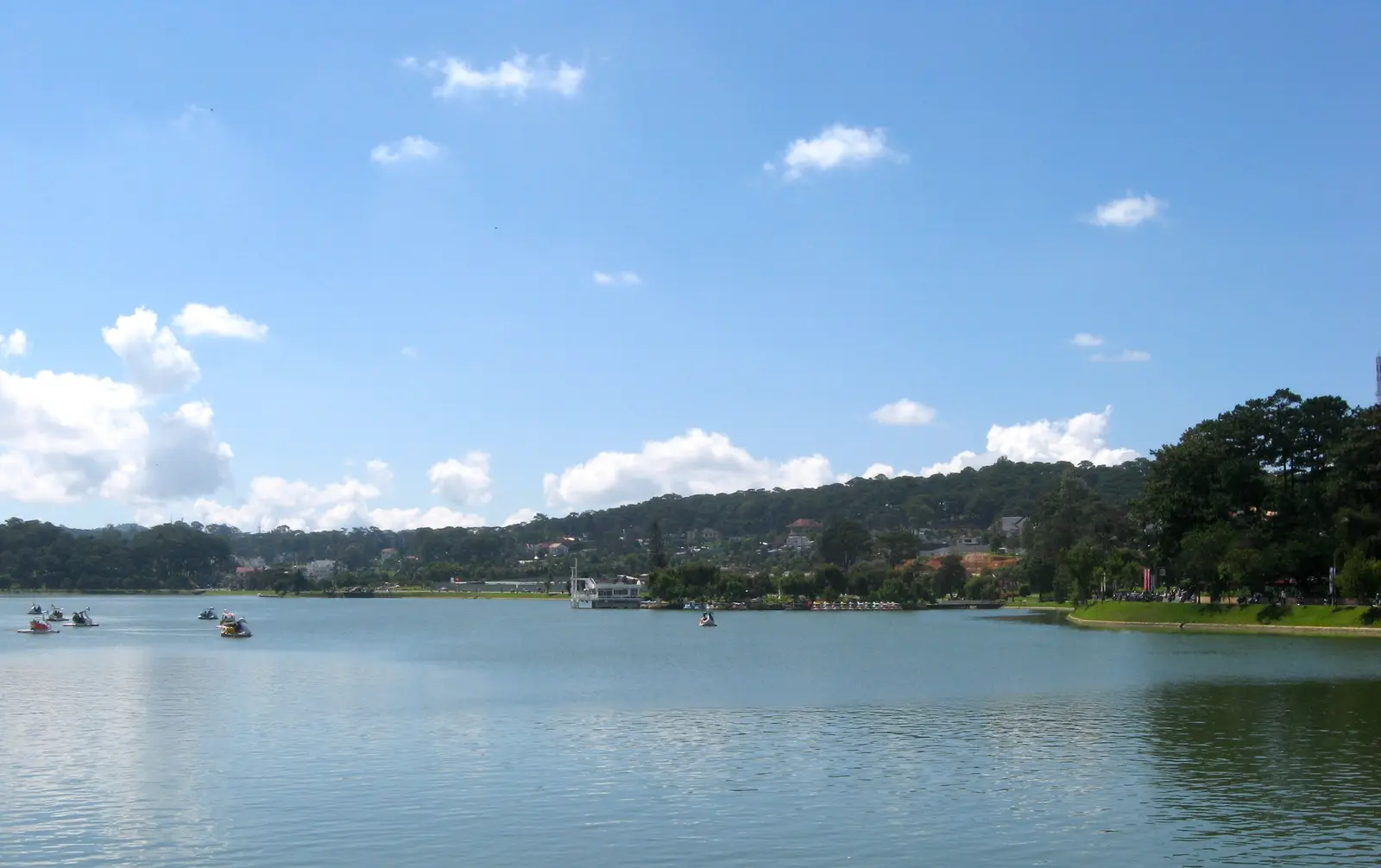 Xuan Huong Lake on a clear day, with pine-covered hills along the far shore