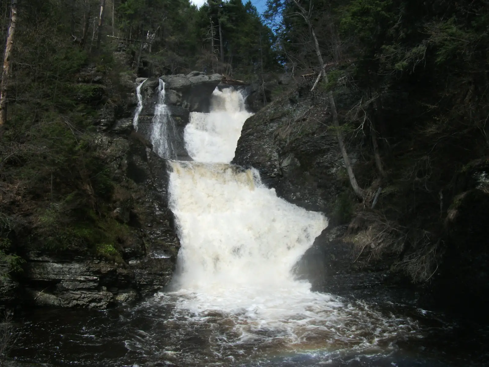 White water pouring down the tiers of Raymondskill Falls between dark rock walls
