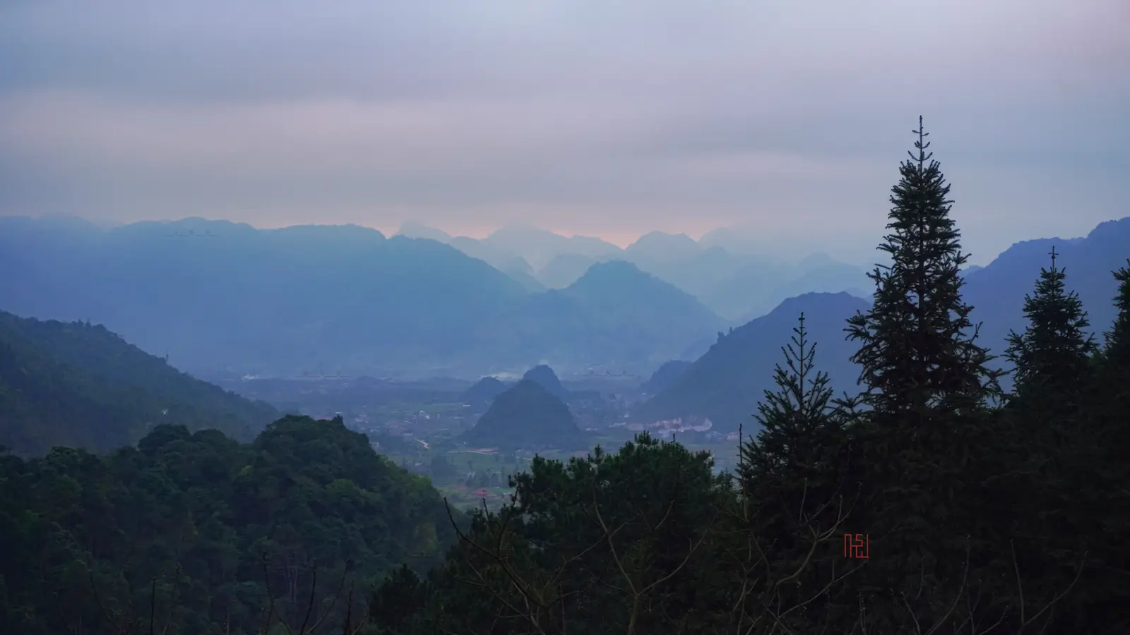 The Tam Son valley and its limestone peaks at dusk, seen through pine trees from above the town