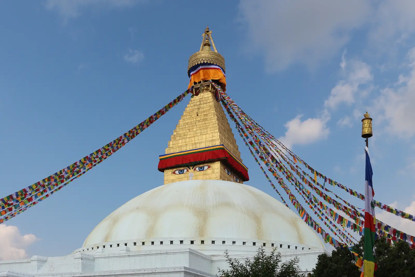 The white dome and gilded tower of Boudhanath Stupa under prayer flags