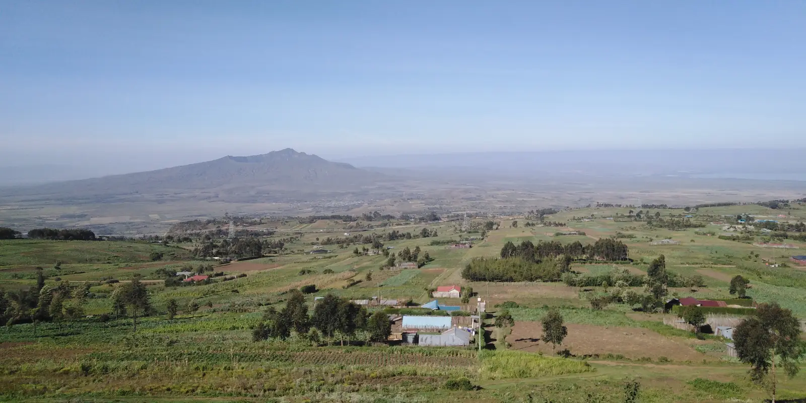 Green farmland on the escarpment above the Rift Valley floor, with Mount Longonot on the horizon