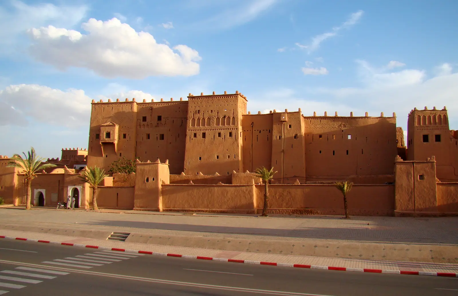The ochre walls and towers of Taourirt Kasbah beside the main road in Ouarzazate