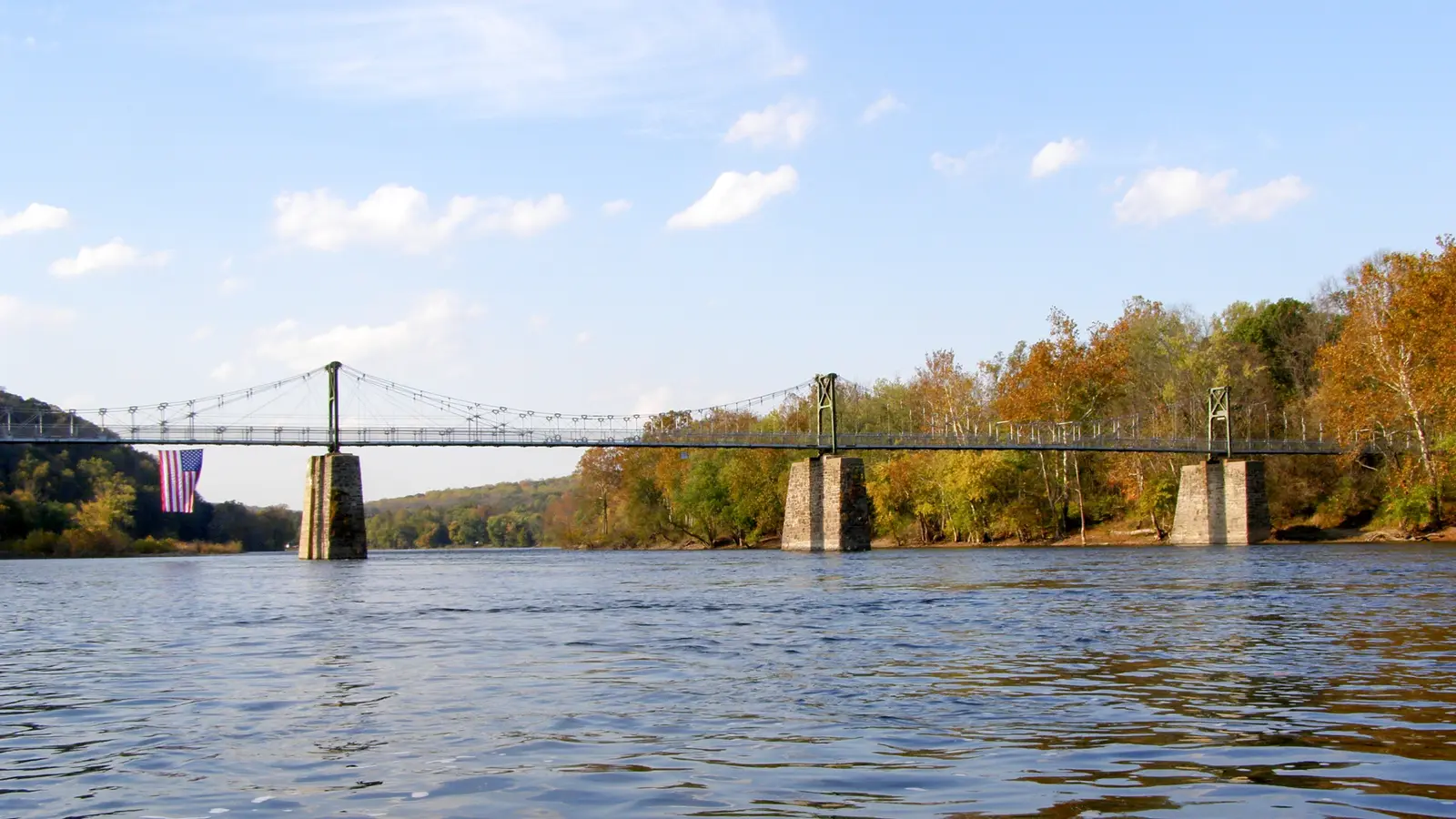 The Lumberville–Raven Rock footbridge spanning the Delaware River between wooded banks in autumn colour