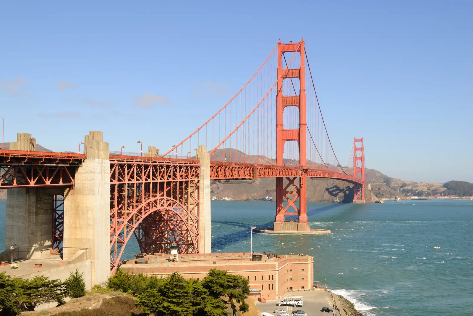 The Golden Gate Bridge from its south end, with the steel arch over Fort Point in the foreground and the Marin Headlands beyond