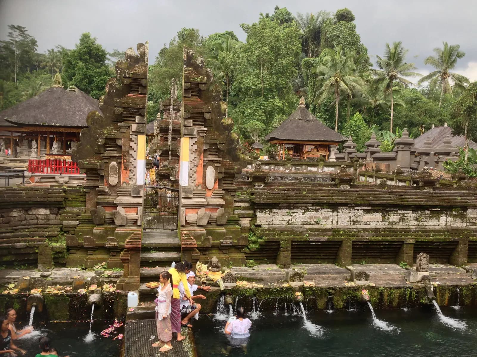 Carved temple gates above the bathing pools of Tirta Empul, where water pours from a row of spouts
