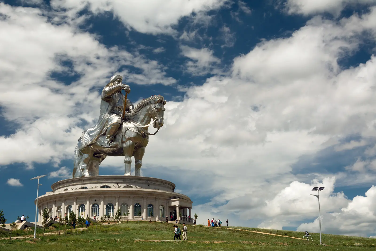 The stainless-steel Chinggis Khaan equestrian statue on its round base under a cloudy sky