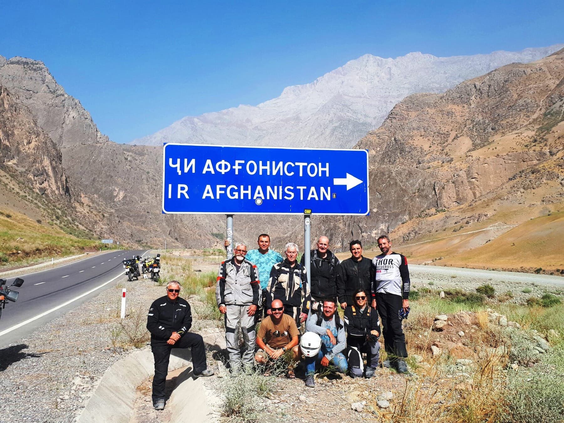 Riders at the Afghanistan border sign on the Pamir Highway, Tajikistan